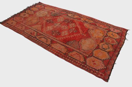 Decorative red and orange patterned rug on a white floor