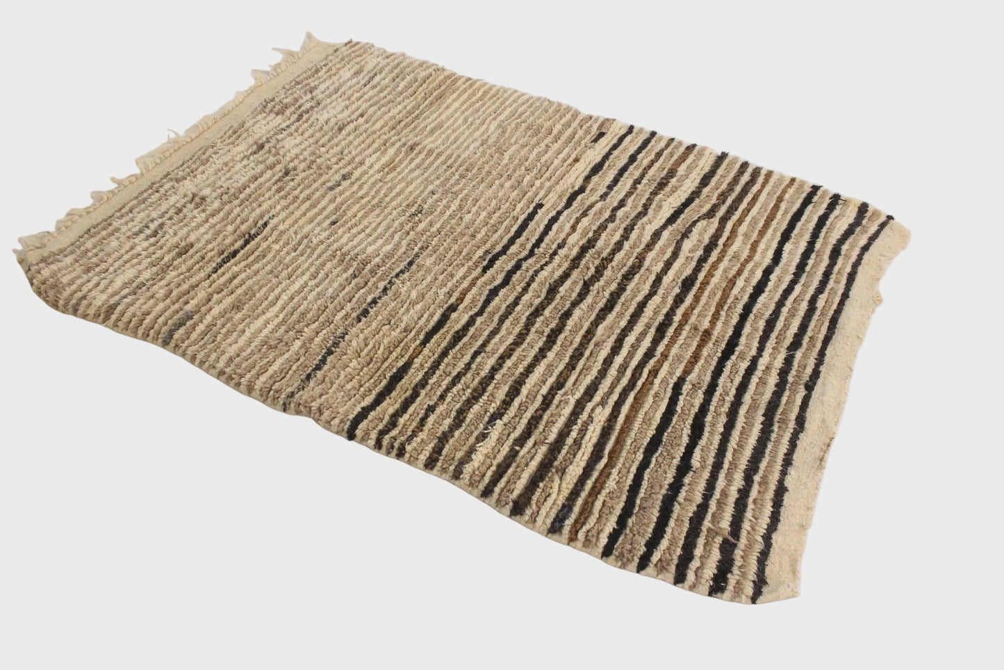A rectangular woven rug with a textured natural beige base and vertical black stripes, laid flat on a white surface.